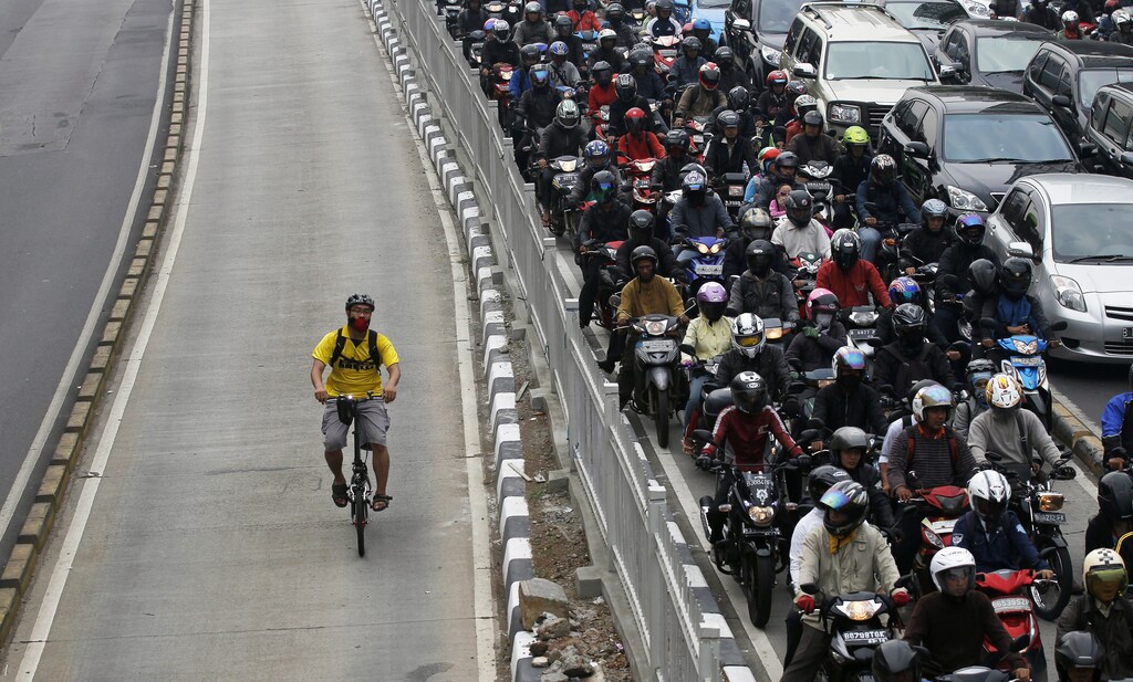 A man rides a bicycle in a bus lane next to a morning rush hour traffic jam in Jakarta November 10, 2011. Indonesia's central bank said on Thursday it saw economic growth in 2012 could slow to below 6.5 percent, as it cut its benchmark overnight interest rate by a surprise 50 basis points to a record low 6 percent to ward off the effect of a slowdown in Europe and China. environment renewable solar energy change transition friendly environment carbon footprint carbon emissions reduction change natural climate change global warming air pollution clean energy power renewables plastic plastics