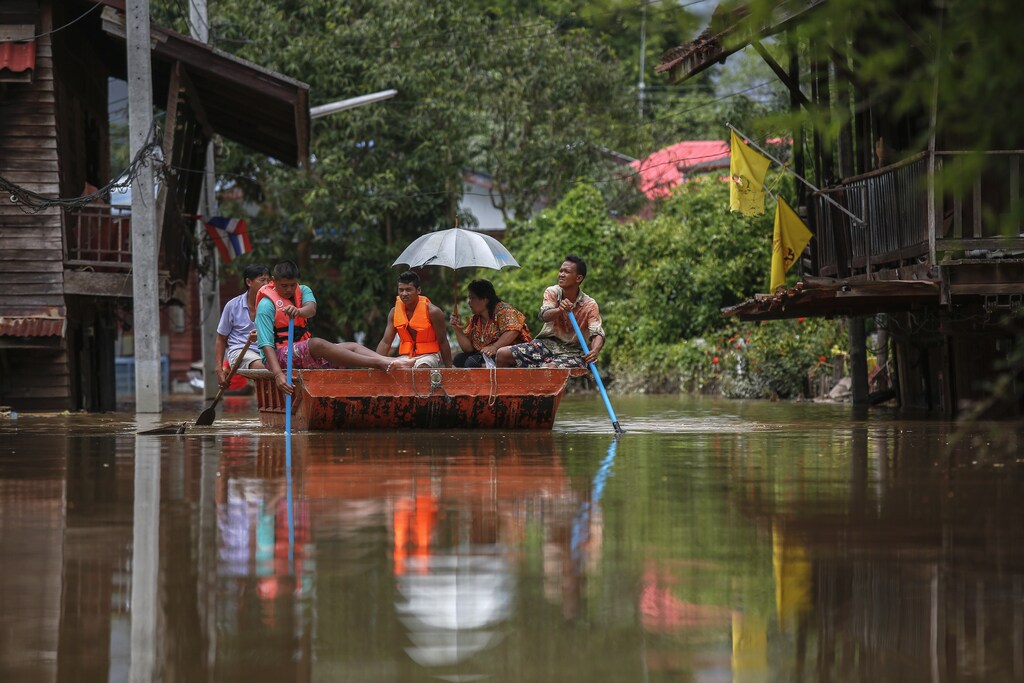 People paddle along a flooded street in Prachinburi, Thailand, in 2013.