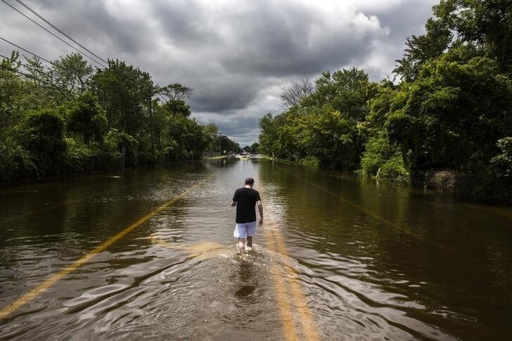 A man walks down a flooded road in Islip, New York August 13, 2014. More than a foot of rain hit parts of New York's Long Island on Wednesday, enough to set a preliminary state record, triggering flash floods and swamping cars on major roads that were turned into rivers during the morning rush hour. REUTERS/Lucas Jackson (UNITED STATES - Tags: ENVIRONMENT DISASTER TPX IMAGES OF THE DAY)