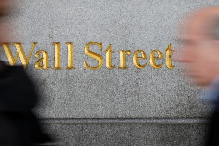 People walk by a Wall Street sign close to the New York Stock Exchange (NYSE) in New York, U.S., April 2, 2018. REUTERS/Shannon Stapleton