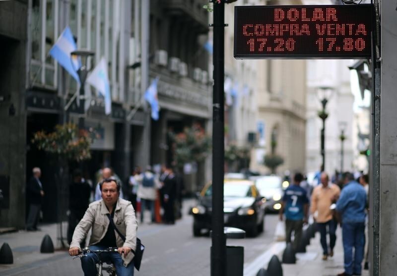A man rides his bicycle past an electronic board showing currency exchange rates in Buenos Aires, Argentina October 4, 2017. REUTERS/Marcos Brindicci - RC1B35049CD0