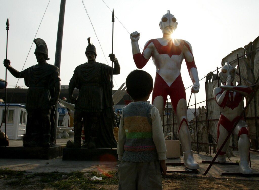 A child looks at an Ultraman, a Japanese science fiction superhero,being displayed beside Roman warriors figures at a moulding factory inGuangzhou, capital of China's Guangdong province, February 11, 2003.Symbols of different cultures stand side by side as manufacturersdevelop the figures world-wide exportation. China's exports rose anannual 18.3 percent to around $315 billion in 2002. Picture takenFebruary 11, 2003. REUTERS/Bobby YipBY/PB - RP3DRINAHRAA