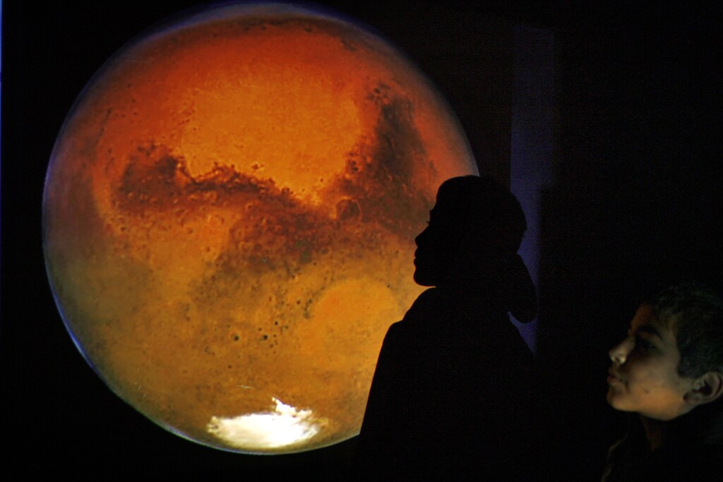 A Jordanian boy poses with an image of Mars projected on a wall during a gathering to watch the red planet in Amman's sky January 28, 2010. REUTERS/Ali Jarekji (JORDAN - Tags: SCI TECH) - GM1E61T0AYQ01