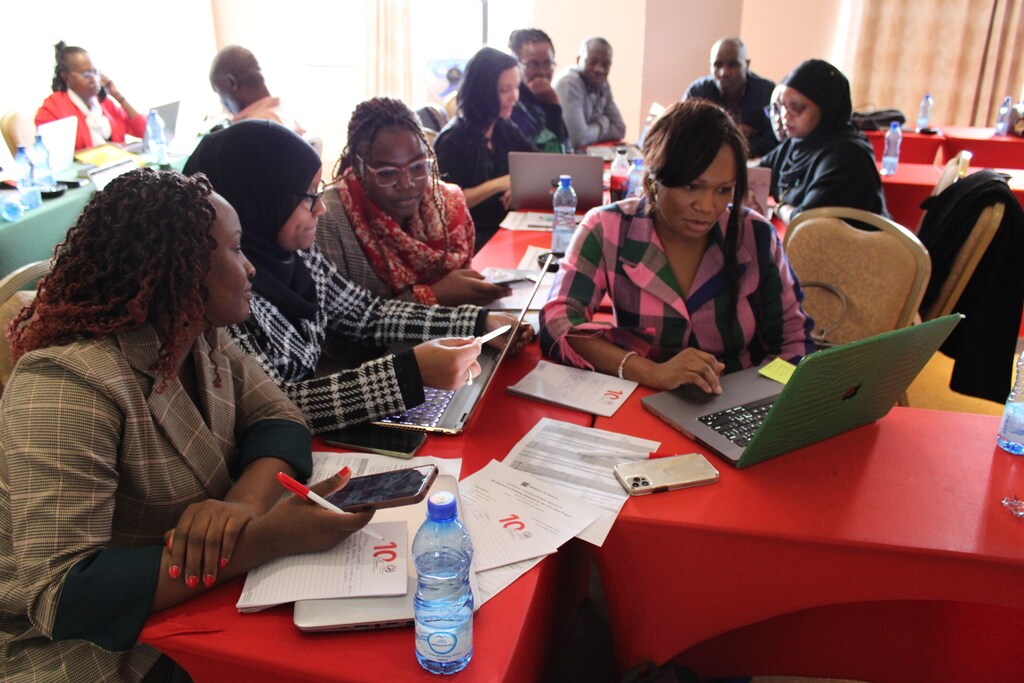 Women gather around laptops, training, cancer care