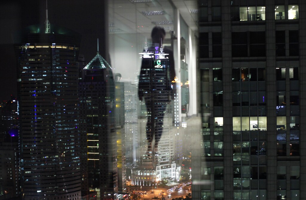 A woman is reflected in a window of an office in the financial district of Pudong in Shanghai September 22, 2011. REUTERS/Carlos Barria