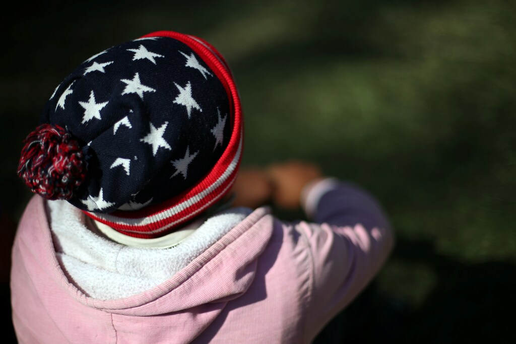 Carlos, a migrant man from Honduras, part of a caravan of thousands traveling from Central America en route to the United States, wears a U.S. flag themed hat as he rests in a makeshift camp in Mexico City, Mexico, November 6, 2018. REUTERS/Hannah McKay - RC19AA1B58D0