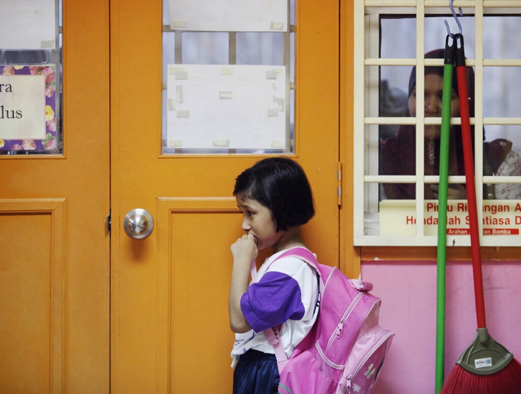 Preschooler Nuranisya Alihasdi, 6, refuses to join her classmates as her mother quietly watches her during the first day of school in Putrajaya outside Kuala Lumpur January 4, 2012. REUTERS/Bazuki Muhammad (MALAYSIA - Tags: EDUCATION SOCIETY) - RTR2VVAL