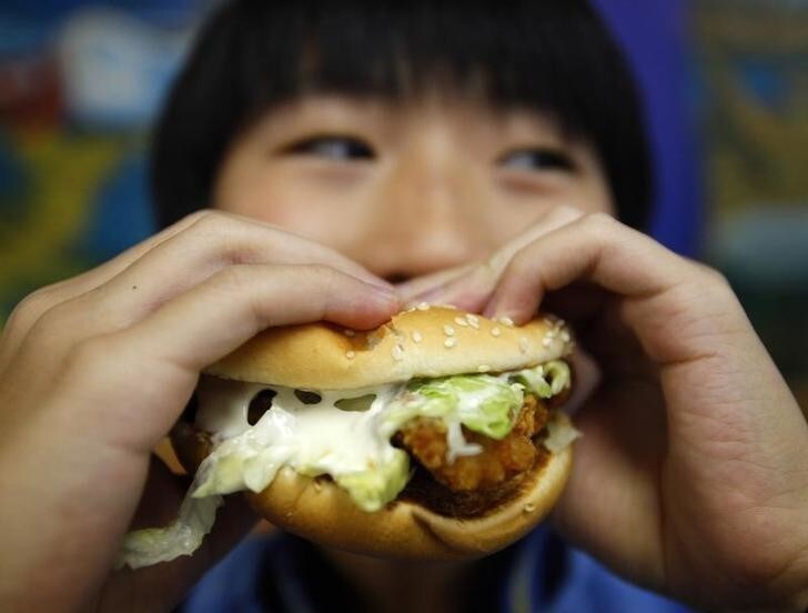 A boy poses with a chicken burger at a fast food outlet in Taipei January 29, 2010. The Taiwan Department of Health on Thursday proposed a ban on junk food advertisements aired around children's television programmes, to tackle the growing child obesity rate, said officials. REUTERS/Nicky Loh (TAIWAN - Tags: SOCIETY FOOD HEALTH MEDIA)