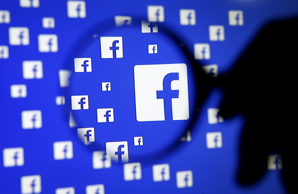 A man poses with a magnifier in front of a Facebook logo on display in this illustration taken in Sarajevo, Bosnia and Herzegovina, December 16, 2015. Facebook Inc said on Wednesday it is testing a service that will allow users of its Messenger app to hail Uber rides directly from the app, without leaving a conversation or downloading the ride-hailing app. . REUTERS/Dado Ruvic TPX IMAGES OF THE DAY - GF10000268231