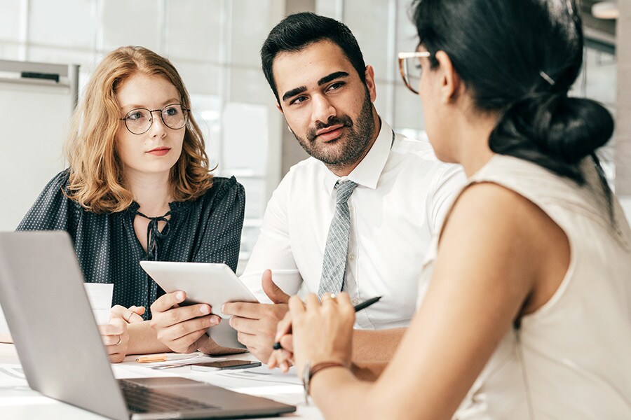 Trust is in short supply on the jobs market – but a global skills passport could help both jobseekers and employers, Pictured are three co-workers holding a discussion in an office setting