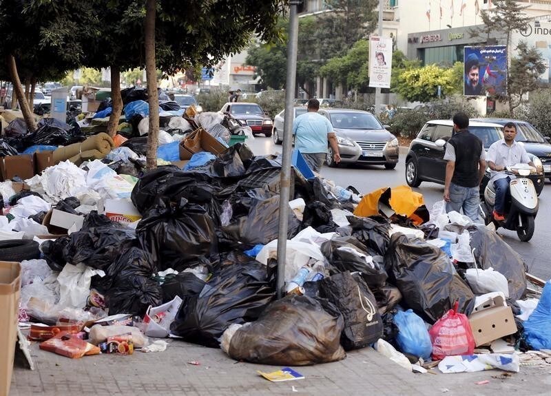 A man on a scooter, pedestrians and cars pass by garbage piled up along a street in Beirut, Lebanon August 26, 2015. The powerful Shi'ite party Hezbollah and its Christian allies walked out of an emergency Lebanese cabinet meeting on Tuesday in protest at a proposed solution to a garbage disposal crisis that has ignited violent protests in Beirut. Public anger that has come to a head over the trash crisis turned violent at the weekend, with scores of protesters and security forces injured. REUTERS/Mohamed Azakir - RTX1PRW2