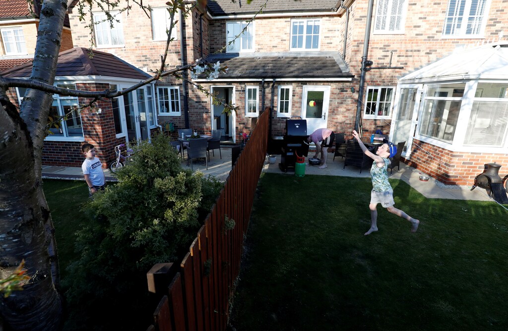Ethan (8) and Fin (9) are seen playing over the fence that divides their gardens, as the spread of the coronavirus disease (COVID-19) continues, Chester-le-Street, Britain, April 11, 2020. REUTERS/Lee Smith TPX IMAGES OF THE DAY - RC2H2G9N6V4G