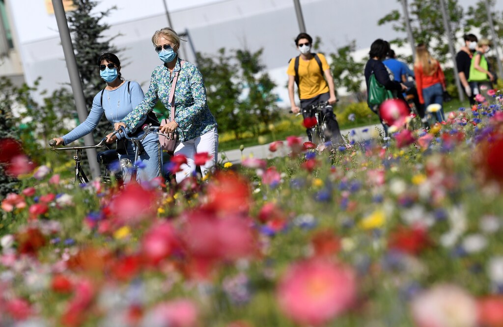 Women wearing protective masks walk with their bikes in the park in the Porta Nuova district, as Italy begins a staged end to a nationwide lockdown due to a spread of the coronavirus disease (COVID-19), in Milan, Italy May 4, 2020. REUTERS/Flavio Lo Scalzo - RC2RHG9V3TWQ