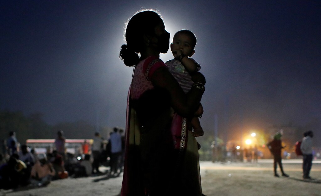 A woman and her baby wait for a bus to take them to a railway station to board a train to their home state of Uttar Pradesh, after a limited reopening of India's giant rail network following a nearly seven-week lockdown to slow the spreading of the coronavirus disease (COVID-19), in Ghaziabad in the outskirts of New Delhi, India, May 18, 2020.