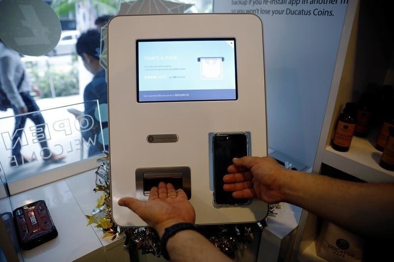 Ducatus franchise manager Philip Lim shows how he makes a deposit at a Bitcoin ATM during the opening of their cashless cafe that accepts cryptocurrencies such as Bitcoin in Singapore December 21, 2017. REUTERS/Edgar Su - RC1724EB4AA0