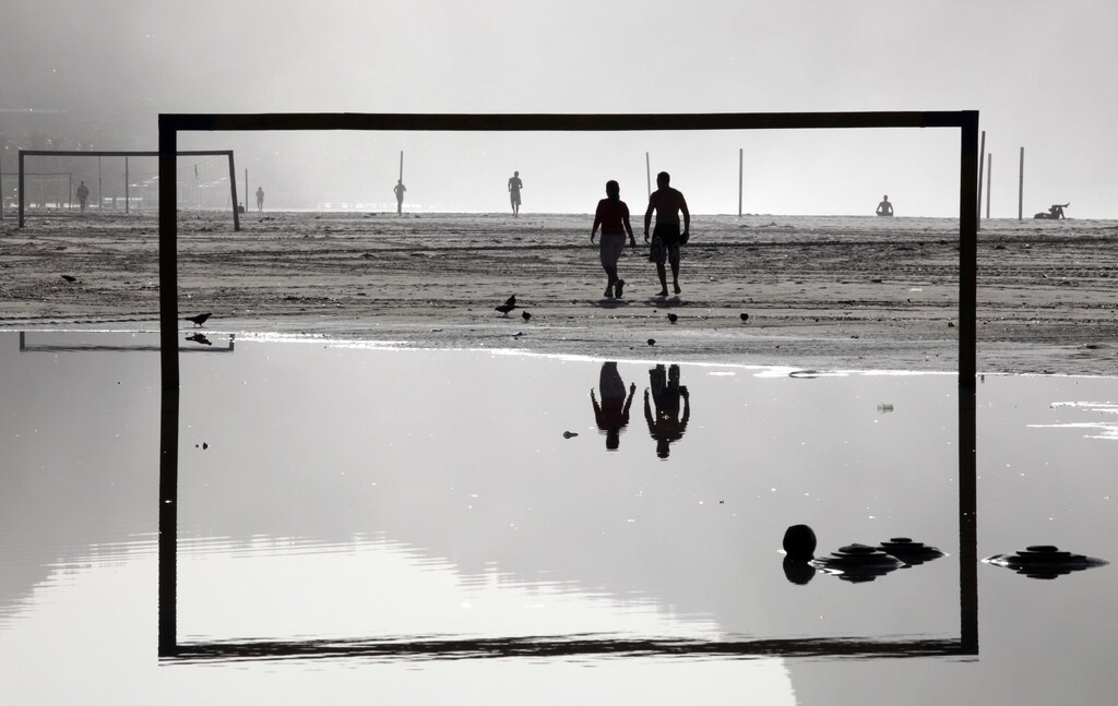 Residents walk near a soccer goal post on Copacabana beach after heavy rains in Rio de Janeiro April 10, 2010. The rains that started on April 5 have killed at least 205 people, most in mudslides that devastated poor hillside communities, and left thousands homeless in and around Brazil's second-biggest city. Rio Mayor Eduardo Paes signed a decree allowing the city to force residents to leave 158 locations the city deems at risk. He had already announced this week the city would remove between 1,500 and 2,000 families from two slums, meeting resistance from some residents' groups. REUTERS/Sergio Moraes (BRAZIL - Tags: SOCIETY ENVIRONMENT DISASTER IMAGES OF THE DAY) - GM1E64A1H5J01