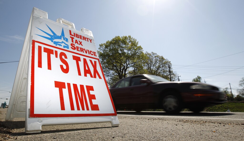 A car passes a sign advertising sign that says 'It's Tax Time'.