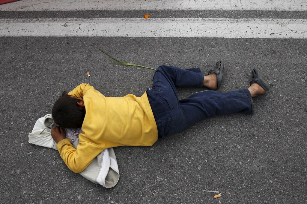 A child sleeps as migrants and refugees block the highway during a protest near the Greek-Macedonian border, near the town of Polykastro, Greece, April 2, 2016. A universal child allowance could help lift children out of poverty.