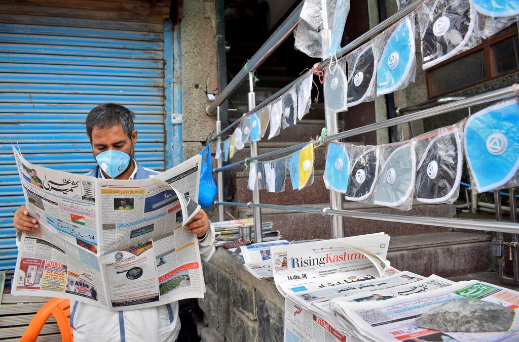 A vendor wearing a protective face mask reads a newspaper at his stall as he sells face masks and newspapers amidst the coronavirus disease (COVID-19) outbreak in Srinagar, September 7, 2020. REUTERS/Sanna Irshad Mattoo - RC2LTI98XD31