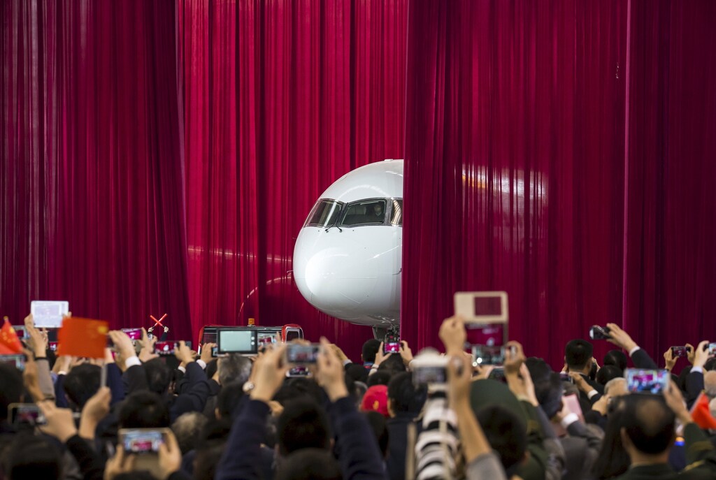 People take pictures and videos as the first C919 passenger jet made by the Commercial Aircraft Corp of China (Comac) is pulled out from behind a curtain during a news conference at the company's factory in Shanghai, November 2, 2015. Comac rolled out China's first homemade 158-seated C919 narrow body jet, which is meant to rival similar models from Airbus Group and Boeing Co. State television also showed footage of the aircraft rolling off the assembly line in Comac's Shanghai factory. In a statement, the company said it had already received 517 orders for the aircraft mainly from domestic firms. Picture taken November 2, 2015. REUTERS/China Daily CHINA OUT. NO COMMERCIAL OR EDITORIAL SALES IN CHINA. TPX IMAGES OF THE DAY. - GF20000043741
