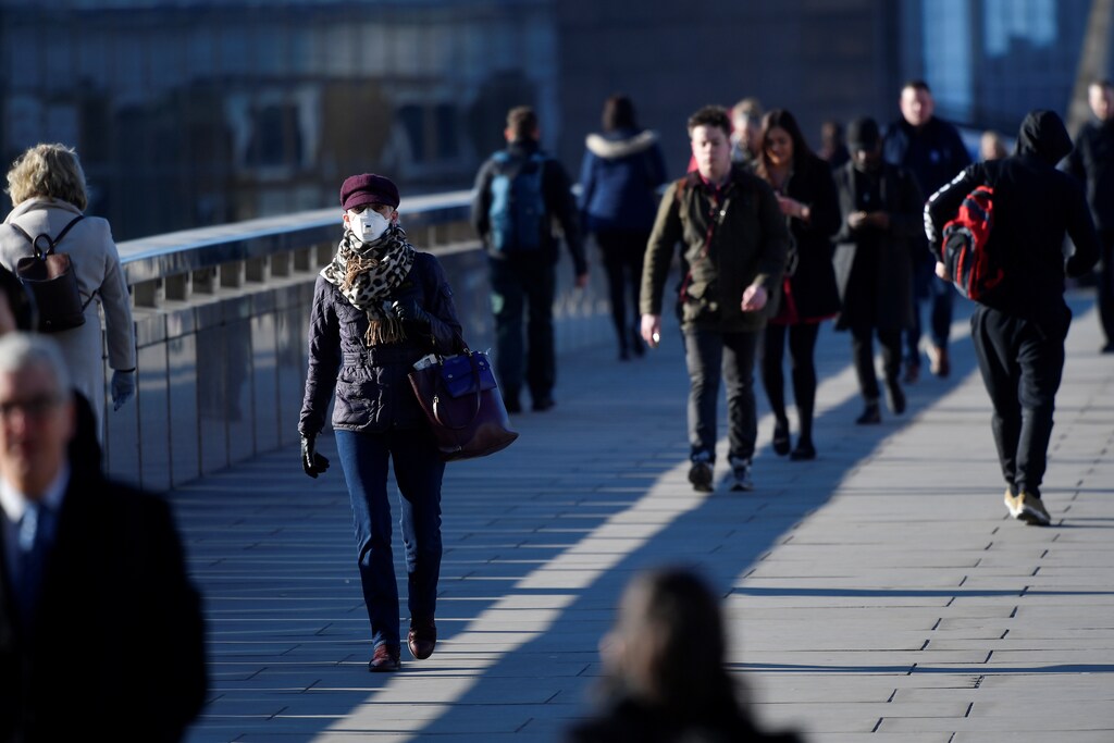 Commuters cross London Bridge with some wearing masks, as the spread of the coronavirus disease (COVID-19) continues, in London, Britain, March 23, 2020. REUTERS/Toby Melville - RC2MPF91KF6B