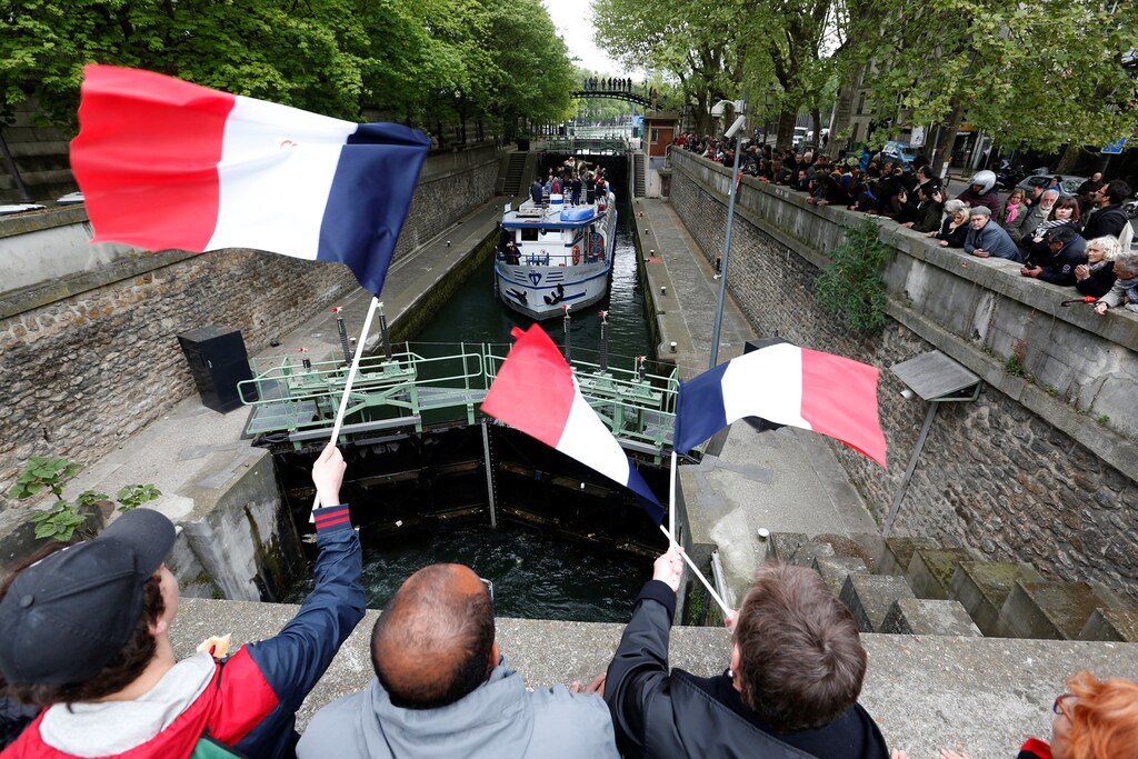 Supporters wave french flags as Jean-Luc Melenchon, candidate of the French far-left Parti de Gauche and candidate for the French 2017 presidential election cruises on a barge on the canal de l'Ourcq in Paris, France, April 17, 2017.