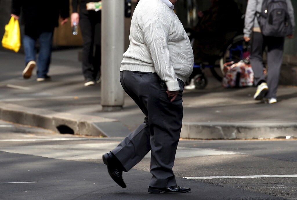 A man crosses a main road as pedestrians carrying food walk along the footpath in central Sydney, Australia, August 12, 2015. REUTERS/David Gray - GF10000172537