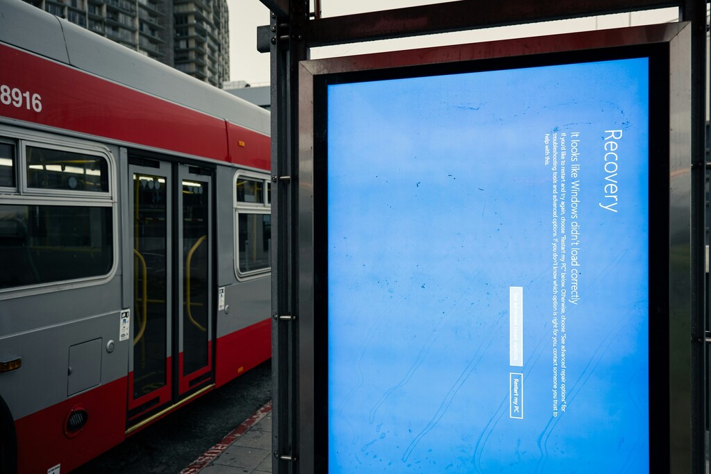 A bus next to a billboard with Windows recovery notice on it in blue: Venture capital firms can encourage startups to prioritize cyber resilience.
