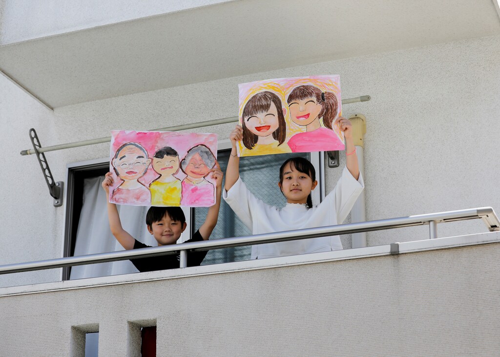 Reku Matsui, 8, and Yaya Matsui, 12, pose for a photograph while holding pictures that they drew during the coronavirus disease (COVID-19) outbreak, as they stand on the balcony of their home in Tokyo, Japan, April 19, 2020. "I miss being with my grandmother and my grandfather. Also, I want to go to my grandmother's house," said Reku, who drew a picture of himself standing in between his two smiling grandparents. Yaya, who drew a picture of herself and a friend said "what I want to do the most right now is hang out with my friends." REUTERS/Kim Kyung-Hoon SEARCH "CORONAVIRUS DRAWING" FOR THIS STORY. SEARCH "WIDER IMAGE" FOR ALL STORIES. TPX IMAGES OF THE DAY - RC2BAG9KZSI9