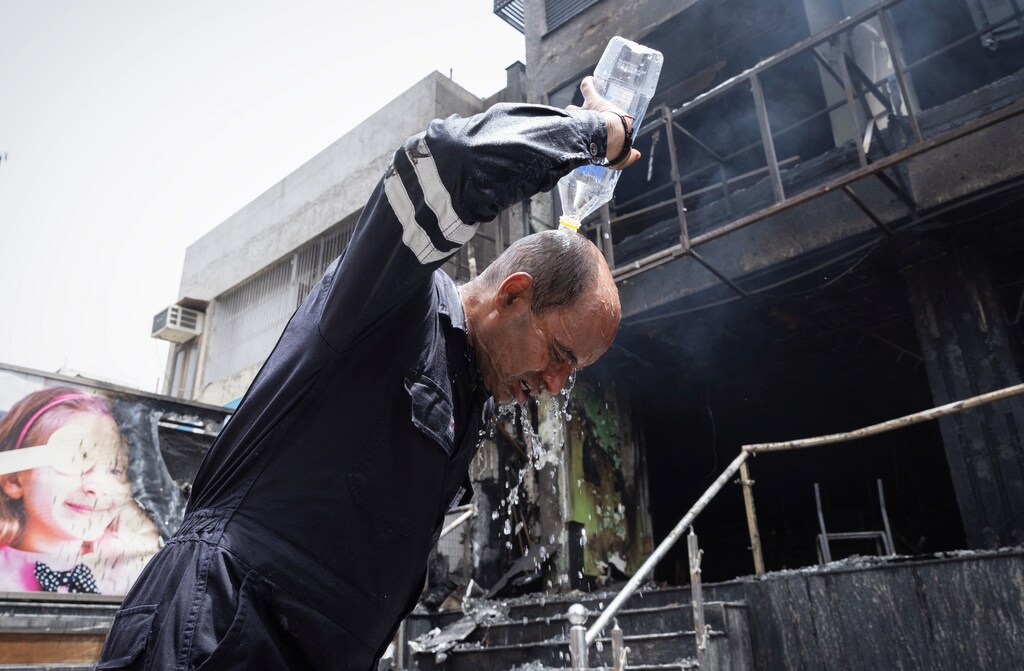Rajesh Dabhas, 43, a firefighter, pours water on his head to cool himself down after coming out of a burning eye hospital in New Delhi, India.