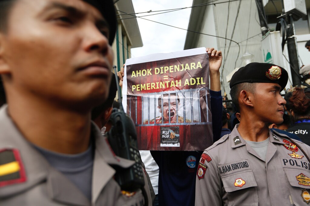 A protester holds a banner outside a court during the first day of the blasphamy trial of Jakarta's Governor Basuki Tjahaja Purnama, also known as Ahok, in Jakarta, Indonesia December 13, 2016. The banner reads, "Ahok in prison = A fair government". REUTERS/Darren Whiteside - RTX2UQS2