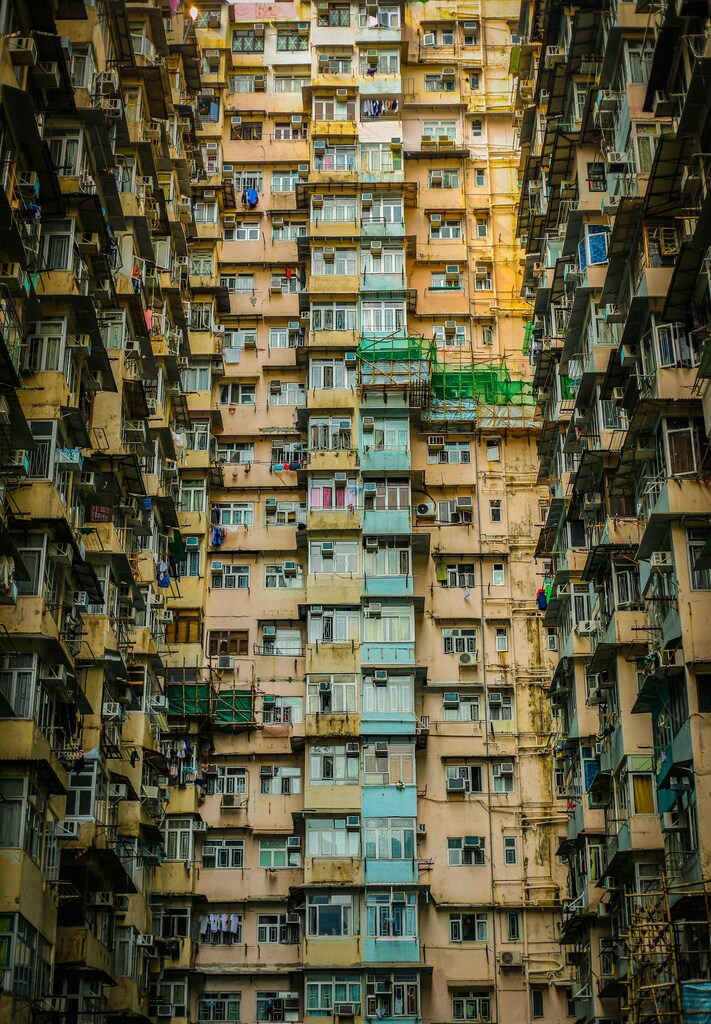 Fotografía en ángulo bajo de edificios de viviendas sociales de color amarillo, azul y topo: La escasez de vivienda se concentra en las zonas urbanas.