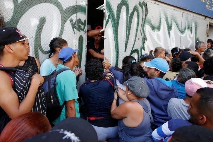 People push a door while they gather to try to buy pasta outside a supermarket in Caracas, Venezuela, June 10, 2016