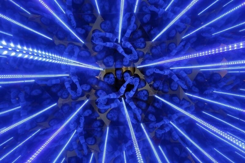 Three women are seen through a giant kaleidoscope as they look inside, as the exhibit is on display to demonstrate the geometric effect of filling space with equal triangles at the "Newton Park" interactive museum of science, during preparations for a performance for school children dedicated to the Russian Day of Science at the Museum Centre in Krasnoyarsk, Siberia, February 4, 2015. A group of young engineers, scientists and researchers, who specialize in chemistry, applied mathematics and physics, founded an interactive museum of science to conduct experiments aimed at the popularization of the exact sciences for pupils and their parents. REUTERS/Ilya Naymushin (RUSSIA - Tags: SCIENCE TECHNOLOGY EDUCATION ANNIVERSARY SOCIETY) - GM1EB241Q0P01
