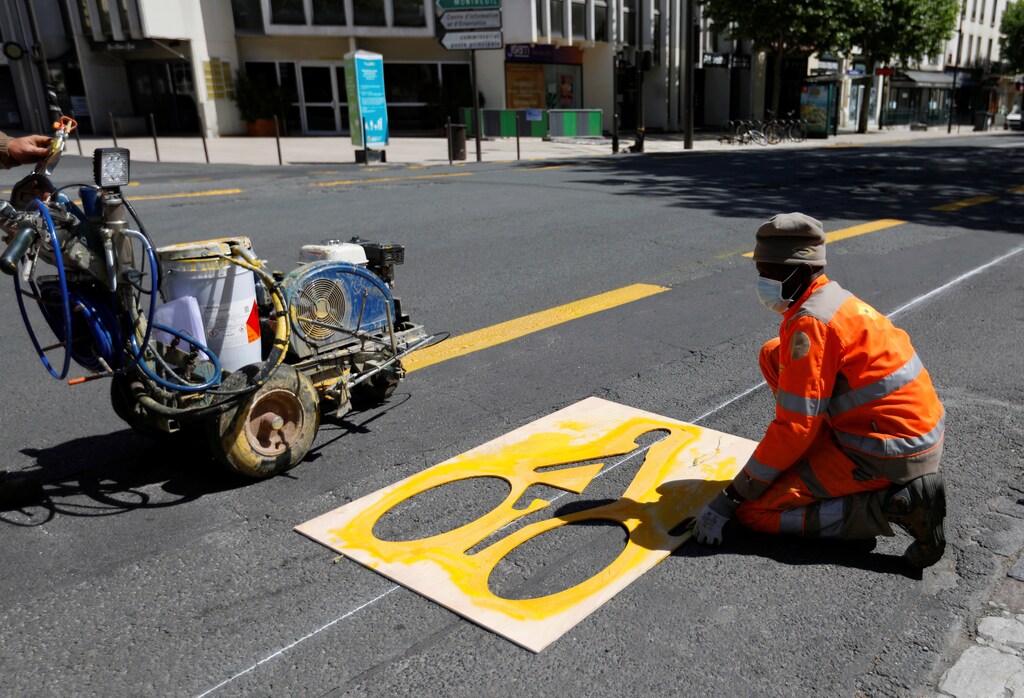 A worker paints a sign representing a cyclist on a new cycling path in Vincennes near Paris prior to the gradual lifting of lockdown restrictions during the outbreak of the coronavirus disease (COVID-19) in France, May 8, 2020. REUTERS/Charles Platiau - RC2DKG9GV0D8