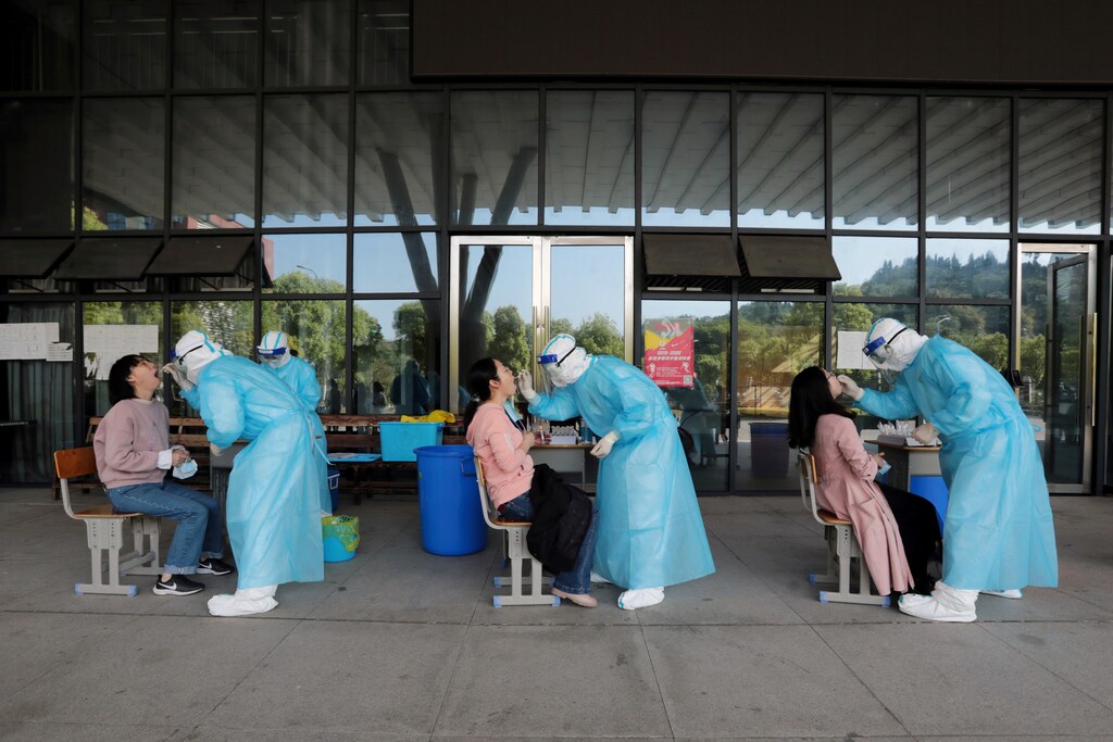 Trabajadores médicos de un hospital recogen hisopos de profesores de secundaria para realizar pruebas de ácido nucleico en una escuela, tras el brote de la enfermedad coronavirus (COVID-19), en Yichang, provincia de Hubei, China, el 27 de abril de 2020.
