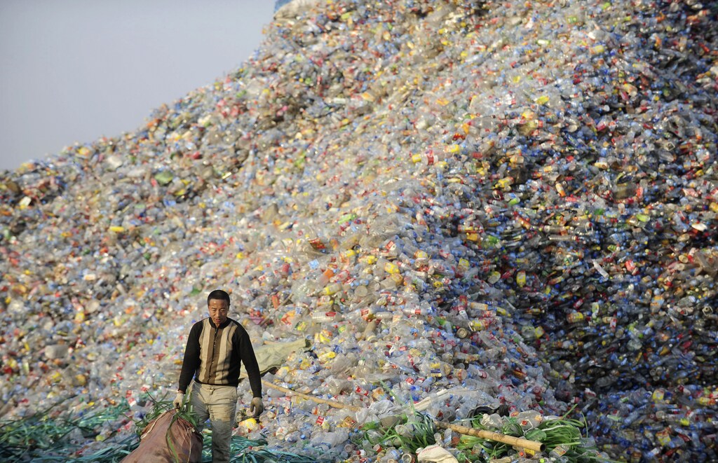 A labourer stands next to a pile of plastic bottles at a recycling centre in Wuhan, Hubei province December 21, 2010. Picture taken December 21, 2010. REUTERS/China Daily (CHINA - Tags: ENVIRONMENT IMAGES OF THE DAY) CHINA OUT. NO COMMERCIAL OR EDITORIAL SALES IN CHINA - GM1E6CM0YLW01