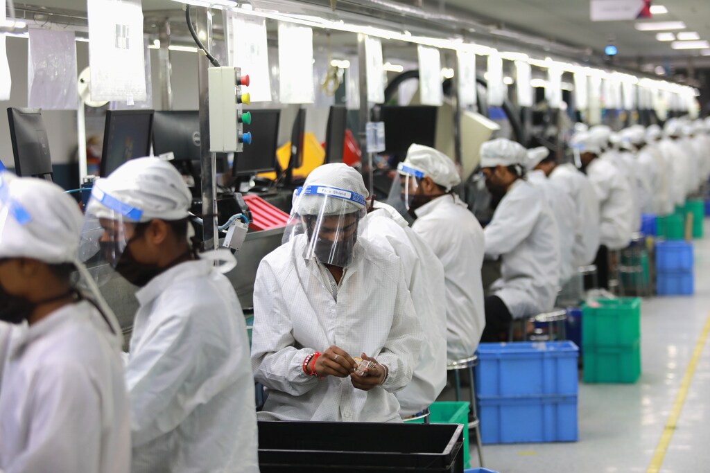 Workers wearing face shields work at an assembly line of mobile phones at Lava International Limited's manufacturing plant, after some restrictions were lifted during an extended nationwide lockdown to slow the spread of the coronavirus disease (COVID-19) in Noida, India, May 12, 2020. Picture taken May 12, 2020. REUTERS/Anushree Fadnavis - RC2FNG903YU7