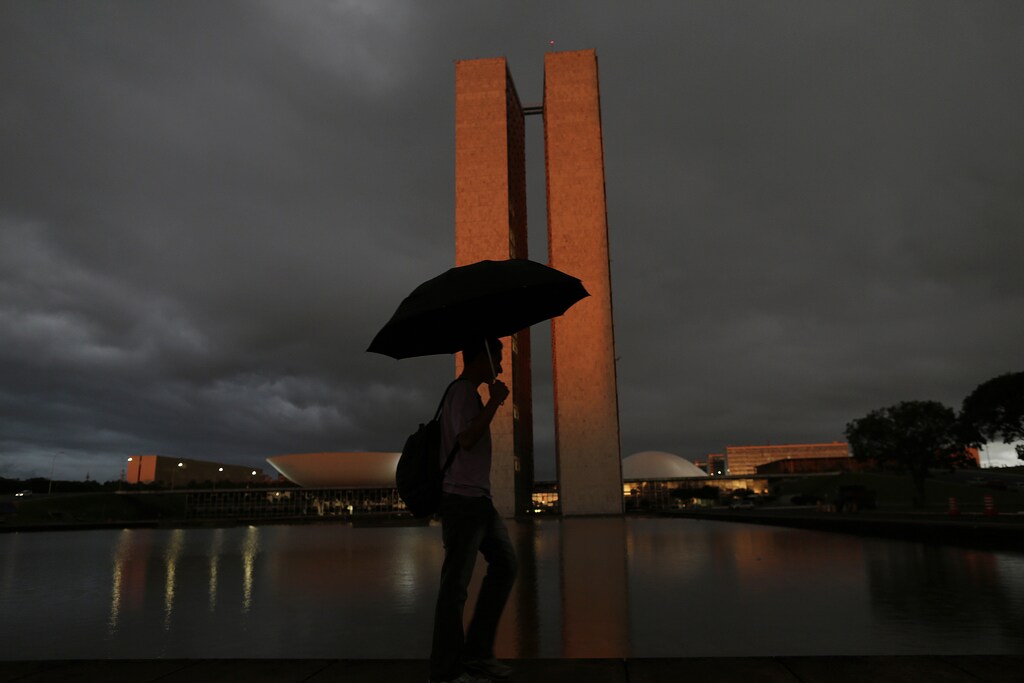 A man with an umbrella walks past Brazil's National Congress headquarters in Brasilia January 22, 2015.