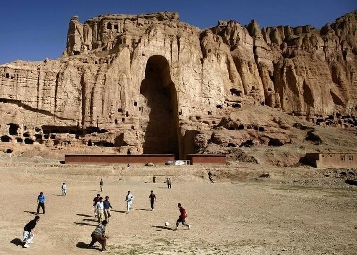 Afghan boys play soccer in front of the gaping niche where a giant Buddha statue used to stand in the central town of Bamiyan some 240 km (149 miles) northwest of Kabul April 13, 2007. The Taliban destroyed two of the statues in 2001. REUTERS/Goran Tomasevic (AFGHANISTAN)