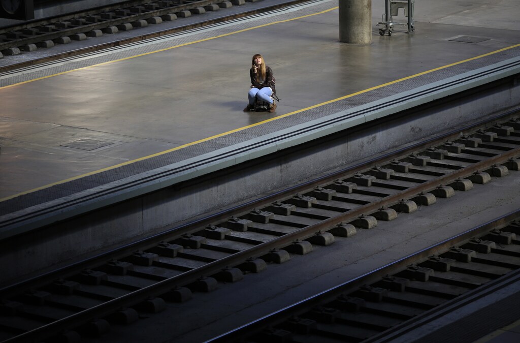 A woman sits on her suitcase as she waits for a train during a 24-hour nationwide train strike against the privatization plans of railways public companies Adif and Renfe at Santa Just train station in the Andalusian capital of Seville, southern Spain October 31, 2013. REUTERS/Marcelo del Pozo (SPAIN - Tags: BUSINESS CIVIL UNREST EMPLOYMENT TRANSPORT TPX IMAGES OF THE DAY) - GM1E9AV1EK101