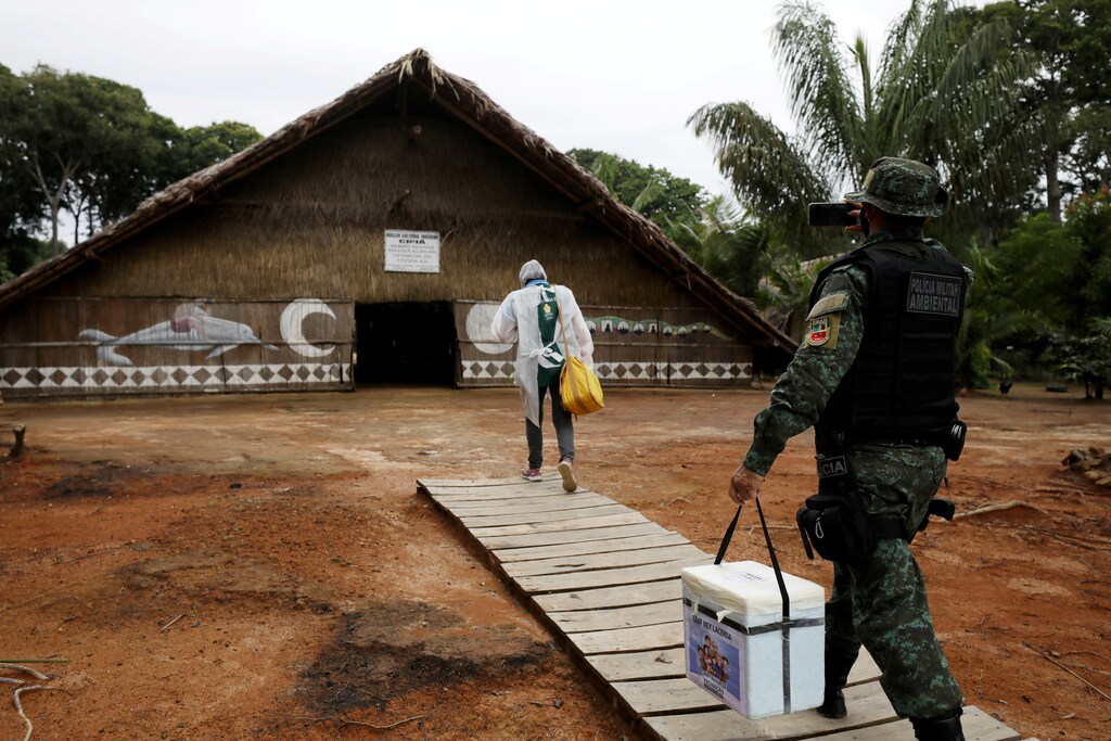 A municipal health worker and an environmental military police officer carry the AstraZeneca/Oxford vaccine as they enter in an Indigenous hut at the the Sustainable Development Reserve of Tupe in the Negro river banks in Manaus, Brazil, February 9, 2021. Picture taken February 9, 2021. REUTERS/Bruno Kelly - RC2PPL92XUT5