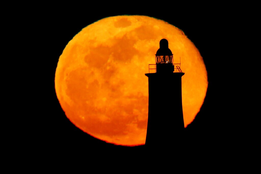 The pink supermoon, the biggest full moon of 2020, rises behind a lighthouse in Valletta, Malta April 8, 2020. REUTERS/Darrin Zammit Lupi - RC2I0G9MIUJM