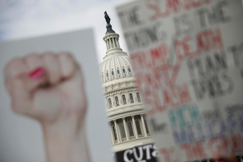Protest signs are seen during a rally against the Republican tax bill on Capitol Hill in Washington, U.S., November 15, 2017. REUTERS/Aaron P. Bernstein - RC1EE7C95D00