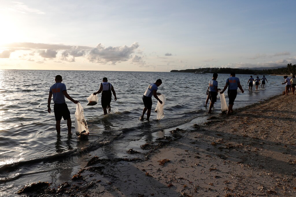 Policemen collect trash in the waters off the beach at the holiday island of Boracay during the first day of a temporary closure for tourists, in Philippines April 26, 2018. REUTERS/Erik De Castro - RC18B5D0F350