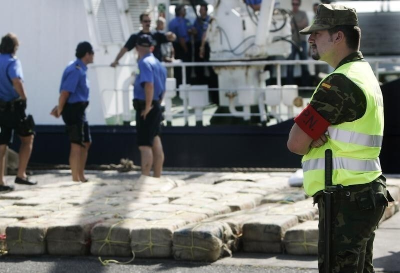A police officer stands next to confiscated sacks of cocaine at the port of Las Palmas, in Spain's Canary Islands, July 26 2005.