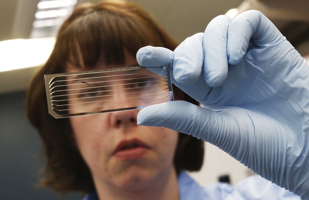 Molecular Genetics Technical Specialist Jaime Wendt looks at a slide containing DNA at the Human and Molecular Genetics Center Sequencing Core at the Medical College of Wisconsin in Milwaukee, Wisconsin, May 9, 2014. Once strictly the domain of research labs, gene-sequencing tests increasingly are being used to help understand the genetic causes of rare disease, putting insurance companies in the position of deciding whether to pay the $5,000 to $17,000 for the tests. Genetics experts say that sequencing more than doubles the chances that families get a diagnosis, and saves spending on multiple tests of single genes. Even if no treatment is found, the tests can also end hugely expensive medical odysseys as parents frantically search for the cause of their child's furtive illness. Picture taken May 9, 2014. To match Insight HEALTH-SEQUENCING/REUTERS/Jim Young (UNITED STATES - Tags: SCIENCE TECHNOLOGY HEALTH SOCIETY BUSINESS) - RTR3UN3X