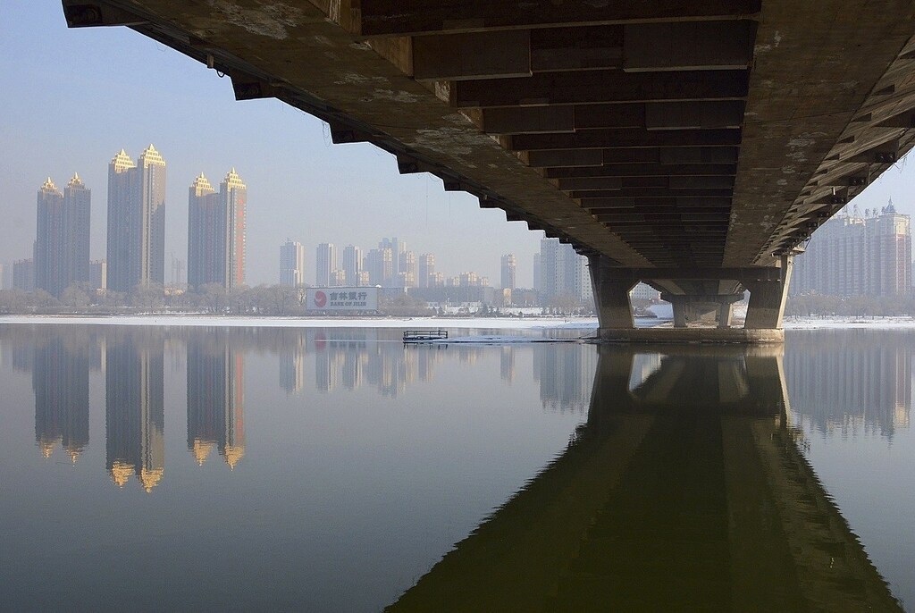 Newly-built residential buildings are seen next to the partially-frozen Songhua River and a bridge in Jilin, Jilin province February 3, 2015. Fourteen Chinese provinces plan to invest a combined 15 trillion yuan ($2.4 trillion) in infrastructure and other projects starting this year as part of their effort to help set a bottom on a slowdown in the economy, an official newspaper said on Wednesday. Picture taken February 3, 2015.