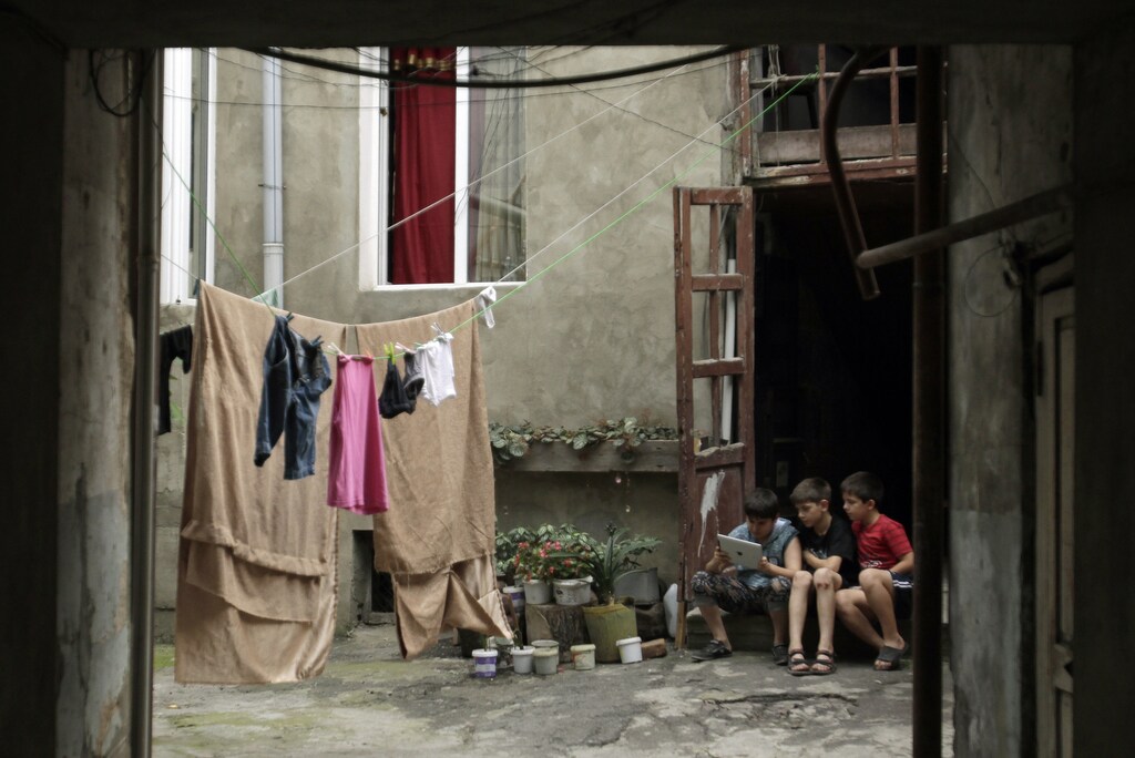 Children use an iPad as they sit in a courtyard in Tbilisi July 18, 2013. REUTERS/David Mdzinarishvili (GEORGIA - Tags: SOCIETY SCIENCE TECHNOLOGY) - GM1E97I1S2V01