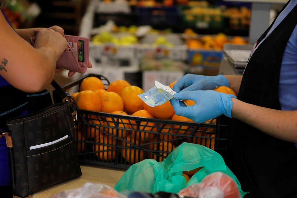 A shopper pays with a 20 Euro banknote and coins to a fruit seller at a fruit store, amid the coronavirus disease (COVID-19) outbreak, in Ronda, southern Spain October 9, 2020. REUTERS/Jon Nazca - RC2AFJ900WTH